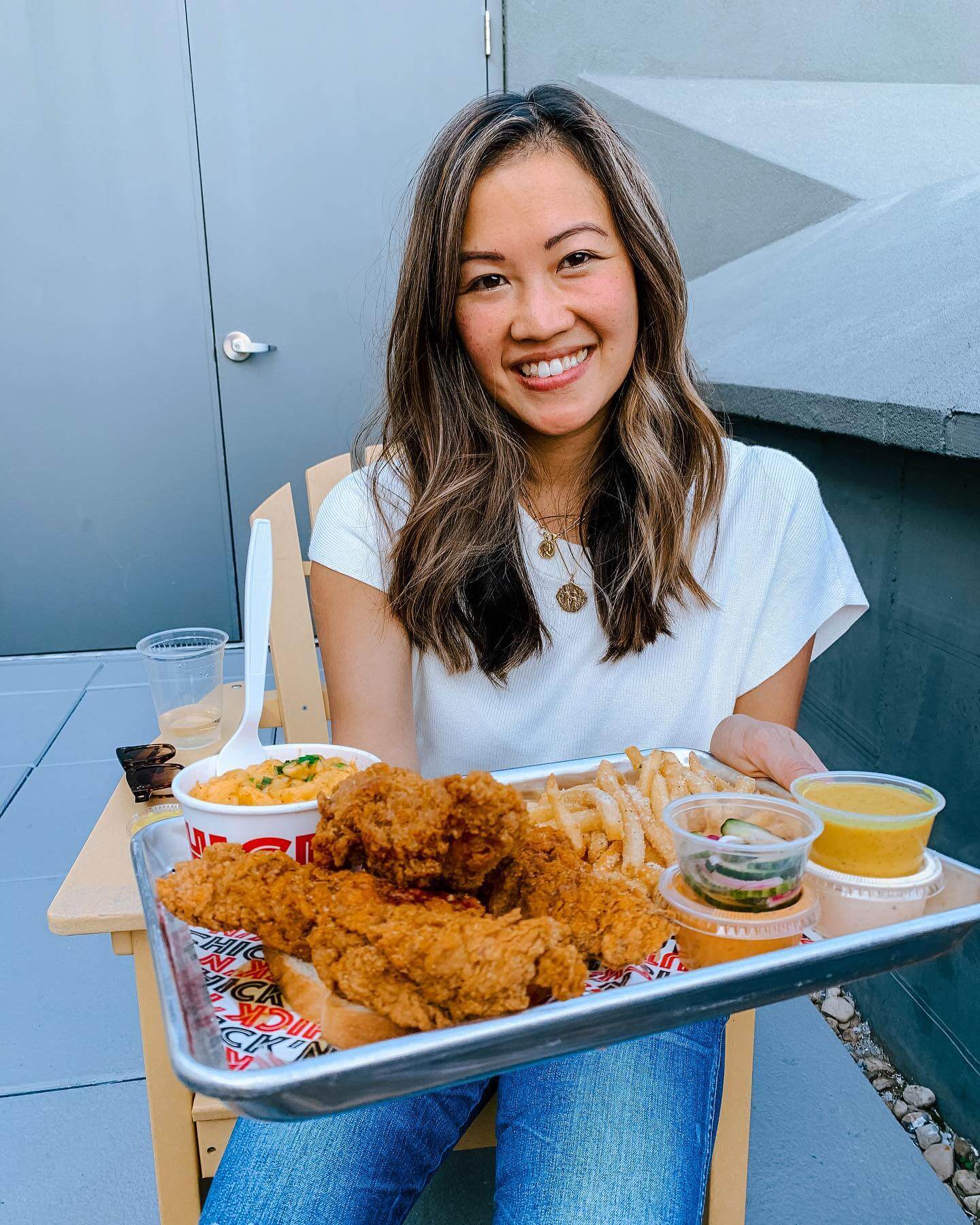 Linh Phillips ’13S (MBA) is in front of a fried chicken meal as she smiles for the camera