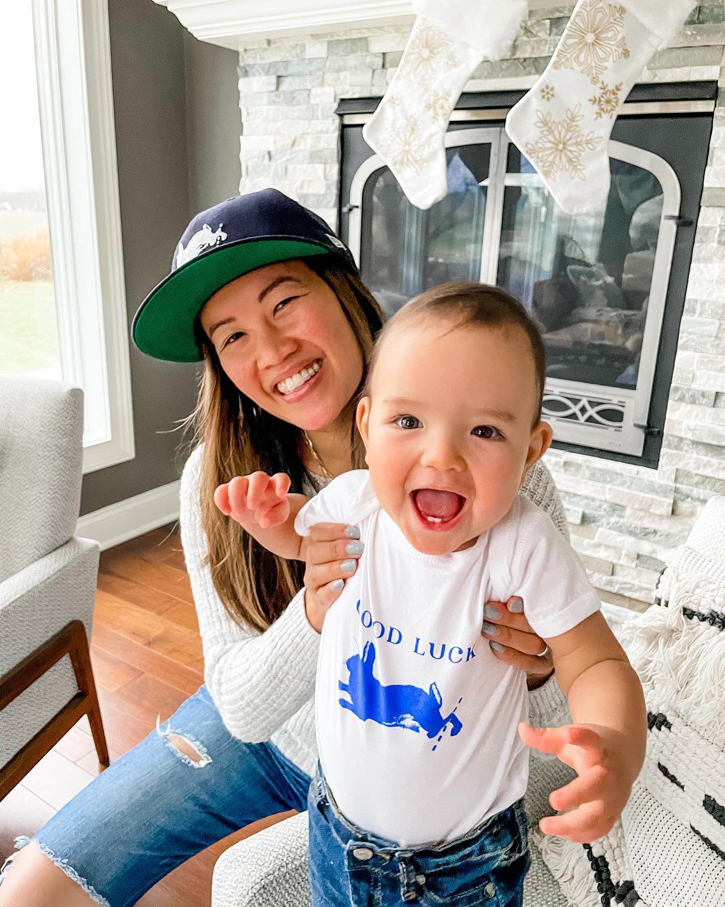 Linh Phillips ’13S (MBA) holding up her son in front of the camera as it takes a picture of both of them smiling