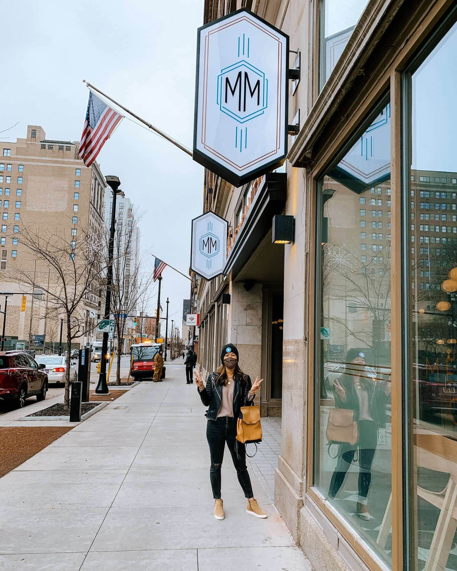Linh Phillips ’13S (MBA) as she stands in front of a restaurant which has a abnner which has the letters MM which