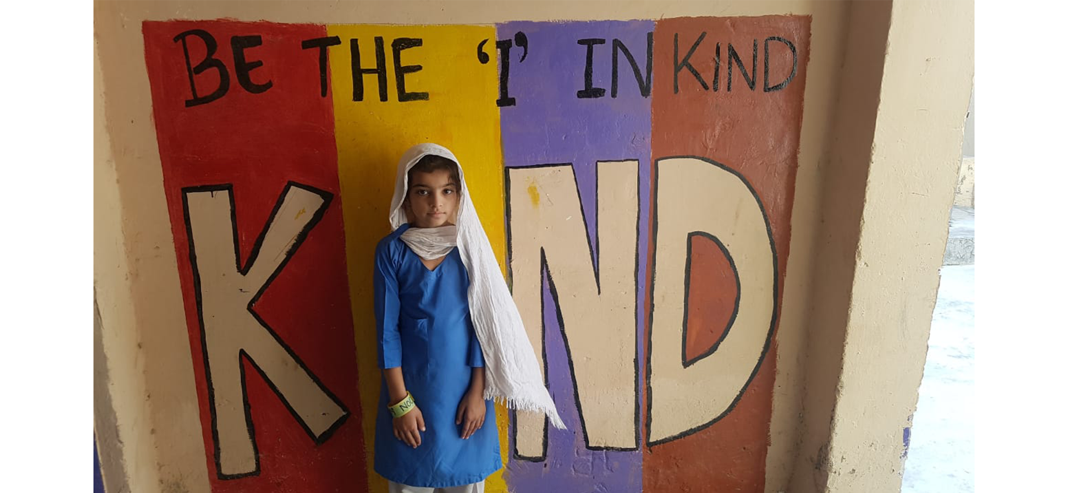 Preschool student standing in front of a wall sign