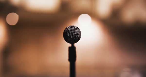 image of microphone from singer's point of view, with blurred audience in background