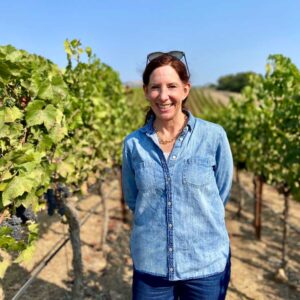 Image of Kerith Overstreet standing in front of a vineyard