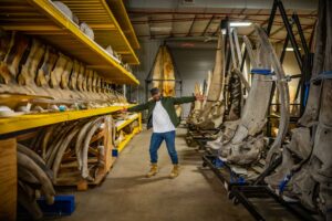 Shane Campbell-Staton ’08 stands arms spread in front of whale skeletons