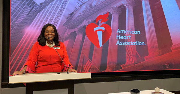 Michelle A. Albert ’94M (MD) standing in front of a projection of the American Heart Association being displayed.