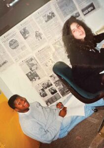 two students working at desks, surrounded by newspaper pages on the walls