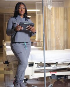 Natalie Lewis ’22N standing in front of a hospital bed and ivy drip