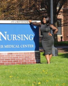 Natalie Lewis ’22N standing in front the School of Nursing URMC sign