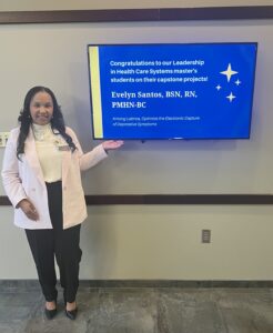 Evelyn C. Santos standing next to a tv monitor with her name on it