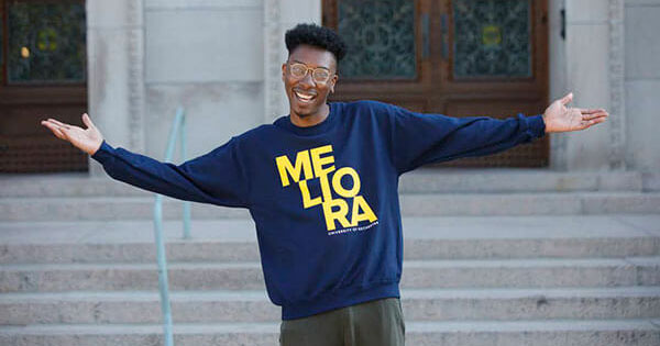 Courtney Thomas, Jr. ’18 poses for a photo while wearing a meliora sweatshirt.
