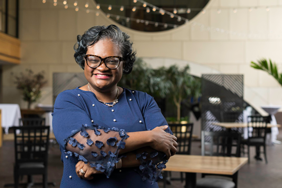 Crystal Sellers Battle stands with her arms crossed, dressed in a blue shirt and wearing tortoise shell glasses.
