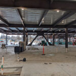 Inside a floor of construction with concrete flooring, metal beams and a metal roof ceiling