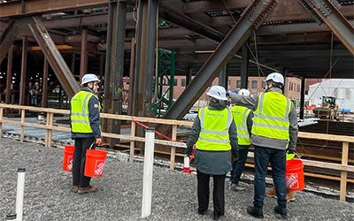 construction site with four people in hard hats and bright yellow vests
