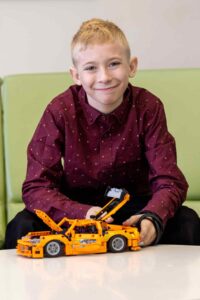 Cody Leavens seated with a yellow toy car on the table in front of him