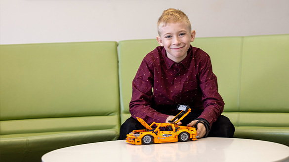 Cody Leavens seated with a yellow toy car on the table in front of him