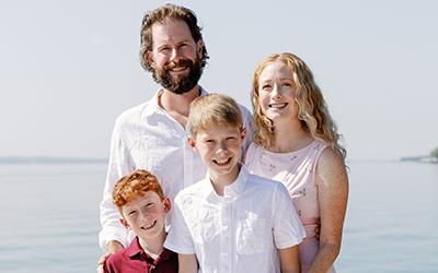 Andrew Lytwynec with his wife Jill, and 2 children posing on a dock with a body of water behind them