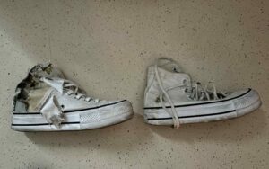 A pair of white damaged sneakers on the ground