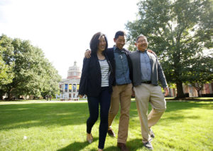 mom and dad walking with son in the quad on a sunny day