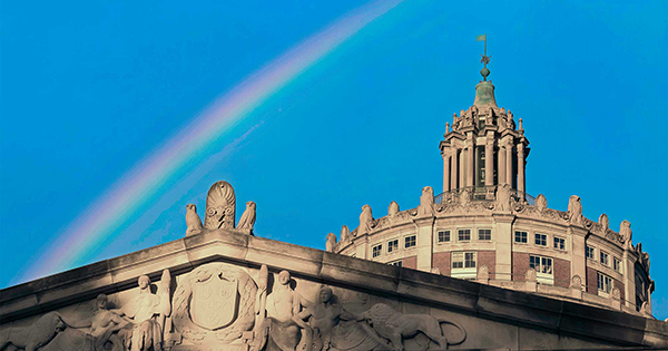 the top of rush rhees tower in front of a blue sky and a rainbow