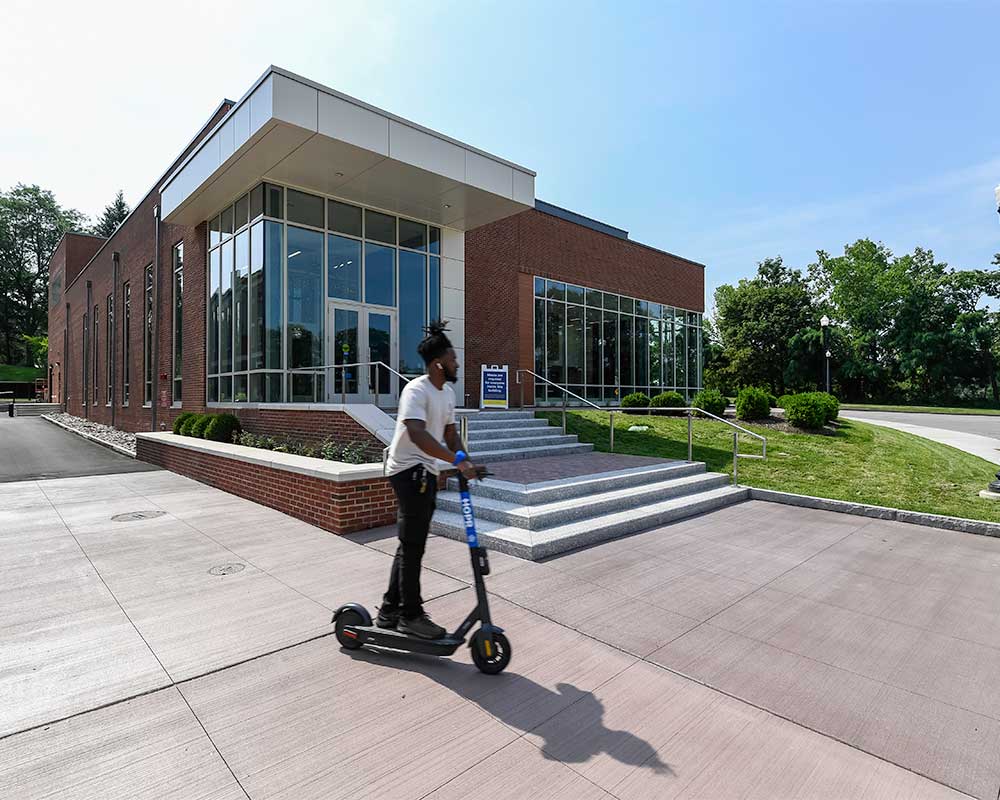 front entrance of the sloan performing arts center with student on scooter riding by the entrance