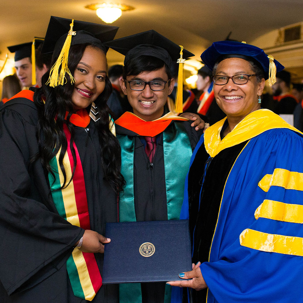 Lisa Norwood in cap and gown posing at graduation with two students