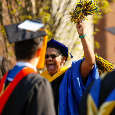 Lisa Norwood in cap and gown raising a pom pom