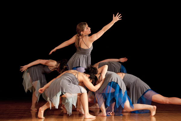 dance troupe performing on stage with arms outstretched