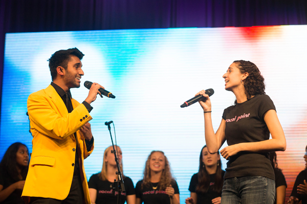 two members of the acapella group singing with microphones in hand