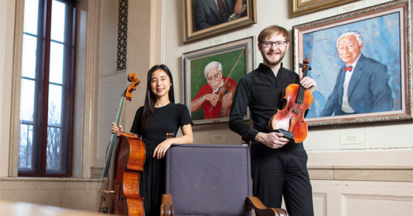 ames Marshall ’21E (MM) and Belle Ra in front of a portrait of John Celentano in the Cominsky Promenade outside Kilburn Hall