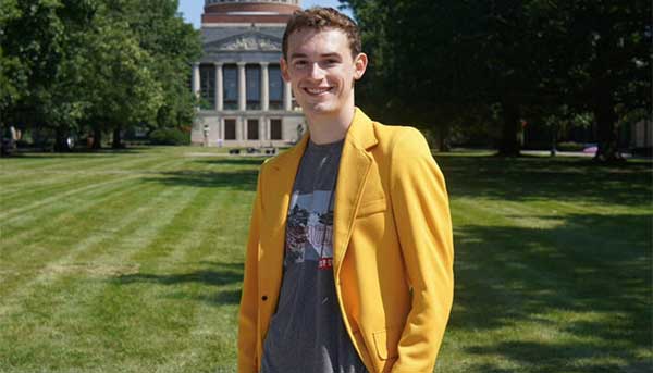 Ethan R. King ’27 wearing yellow blazer in quad in front of Rush Rhees library