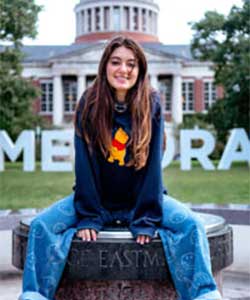 Celia Konowe sitting on sun dial in middle of quad in front of rush rhees