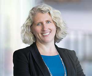 portrait of Nicole Sampson wearing a dark blazer and blue shirt
