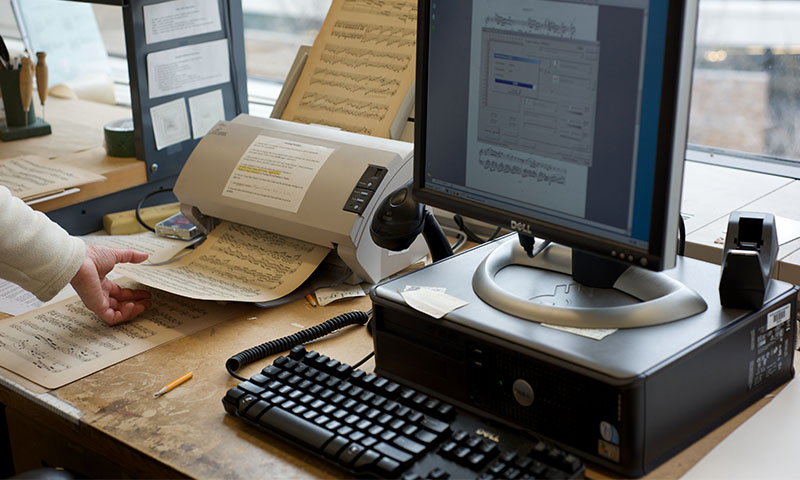 Computer monitor, key board, and a printer printing out music sheets