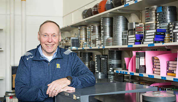 Terry Gurnett posing in front of shelves of film reels