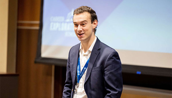 Ian Krager in a suite jacket in front of screen speaking to a group