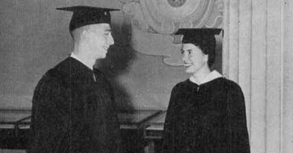 Black and white photo of 2 people in gradutaion cap and gown looking at each other