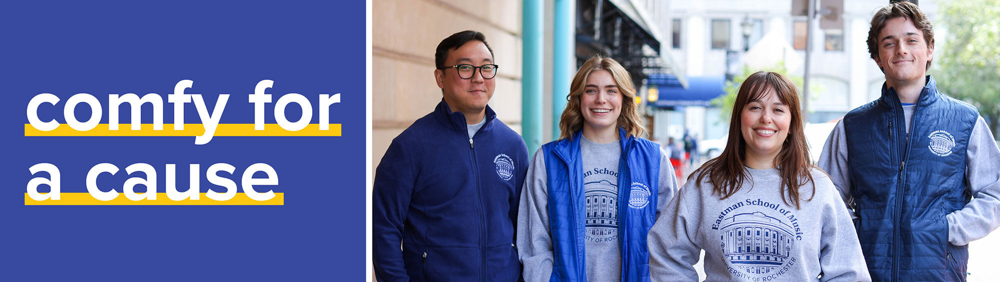 Students and staff model Eastman School of Music sweatshirts and vests indoors beside the campaign slogan “comfy for a cause.”