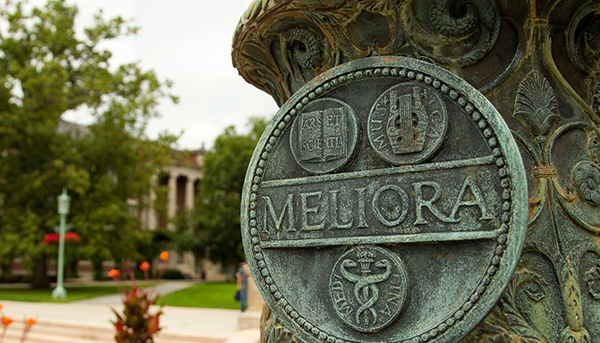 Meliora flagpole with the sigil carved in with River Campus in background