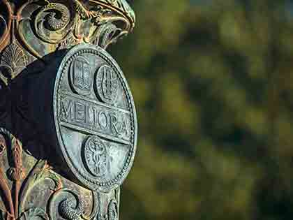 meliora flagpole against a blurred green background