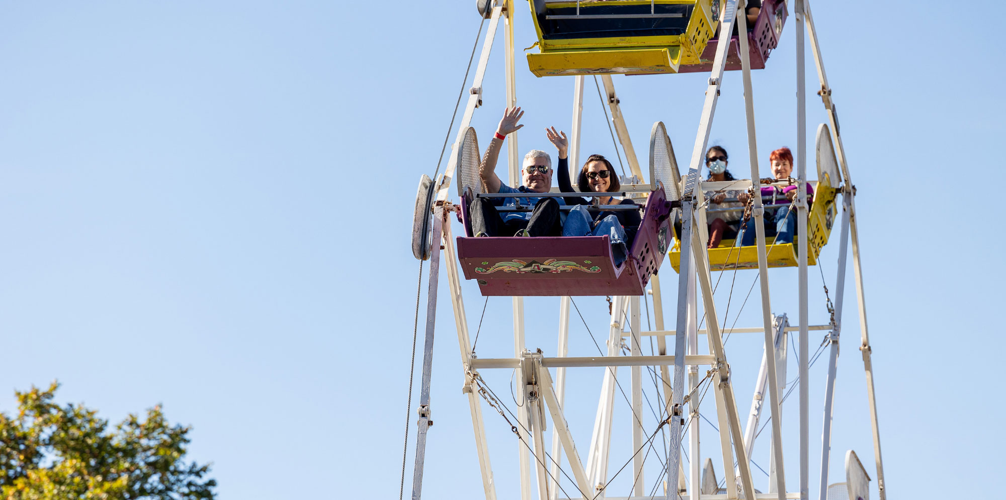 People on a ferris wheel for meliora weekend against a light blue sky