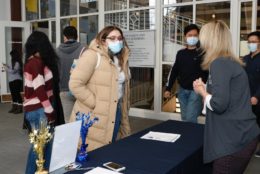 woman wearing tan puffy jacket checking in a table