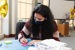 woman wearing mask filling out a sticky note at table