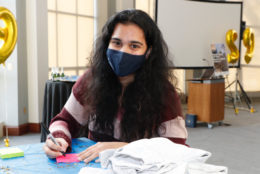 woman wearing mask filling out a sticky note at table