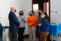 five people wearing masks in a discussion
