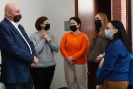 five people wearing masks in a huddle speaking