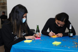 two women filling out sticky notes at table