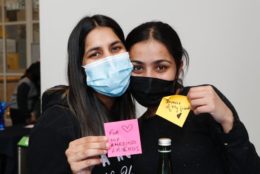 two woman in masks posing with sticky notes