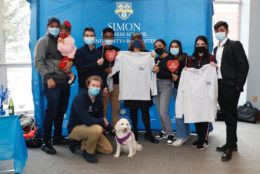 large group of students all in masks posing in photo booth and a dog