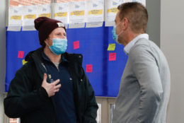 two men speaking both wearing masks