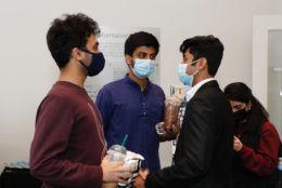 three men huddled around wearing masks and drinks from starbucks