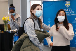 two women in foreground, one woman in background, all wearing masks